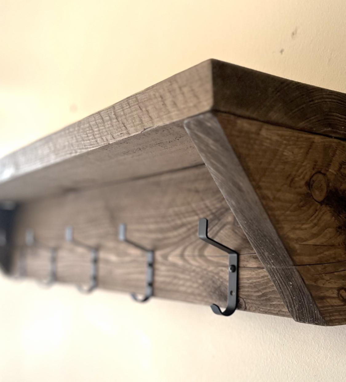 Farmhouse style wooden shelf with hooks on a neutral background (side view)