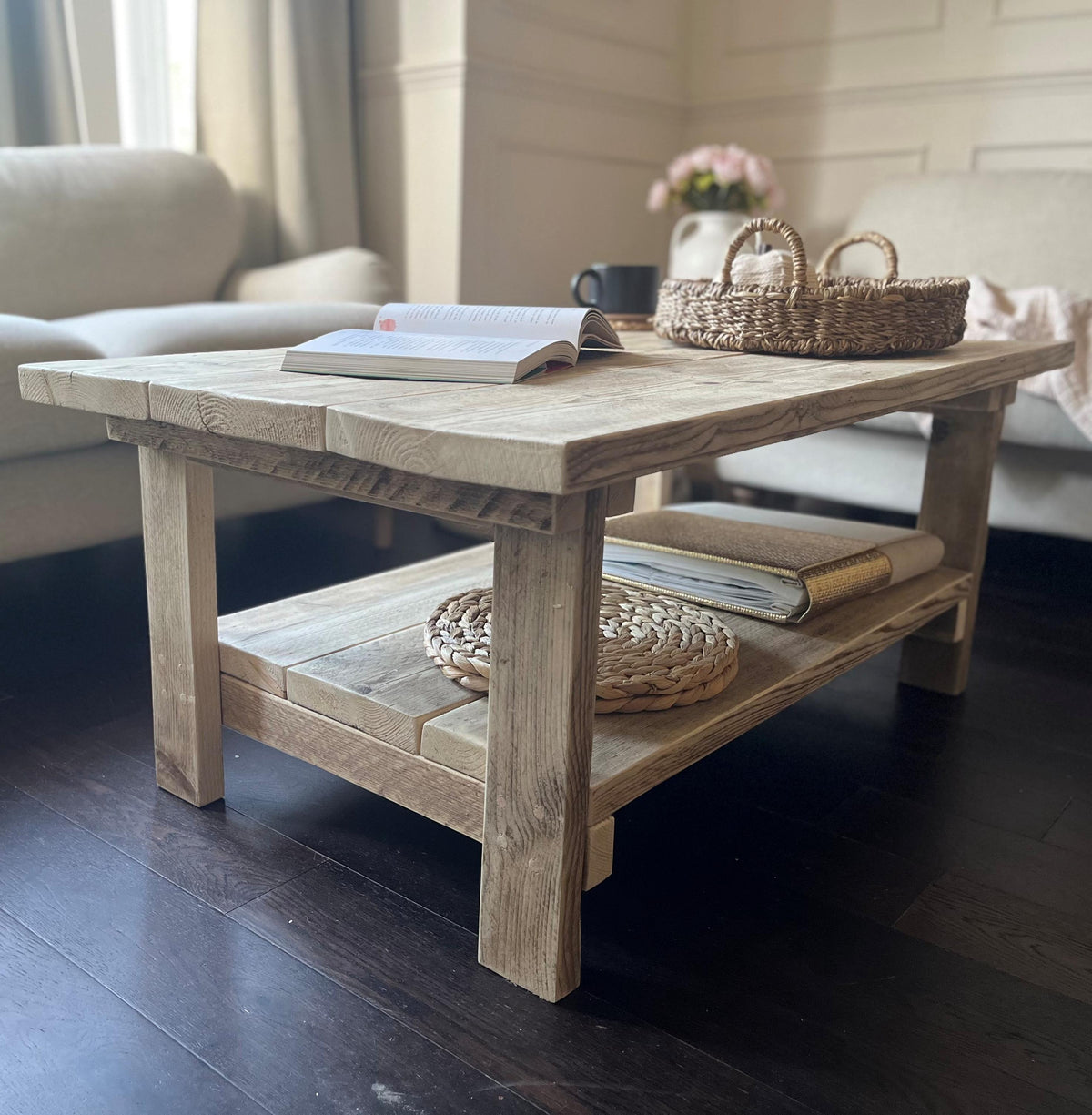 Rustic wooden coffee table with books and a basket in a living room setting.