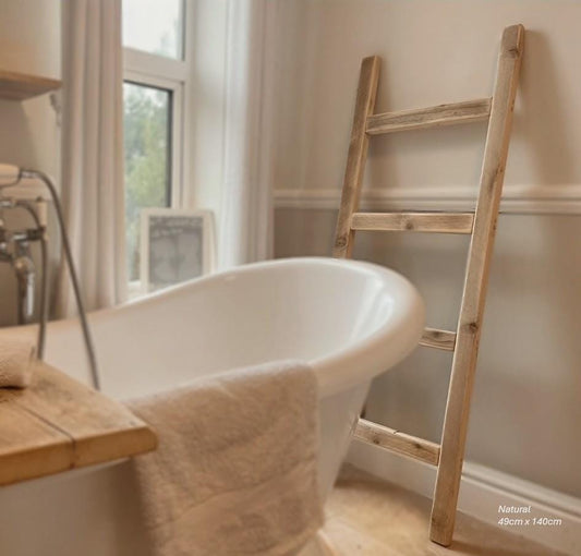 White freestanding bathtub with a wooden ladder against a wall in a bathroom.