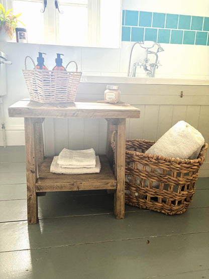 Bathroom setting with a rustic wooden  side table that includes a bottom shelf.  