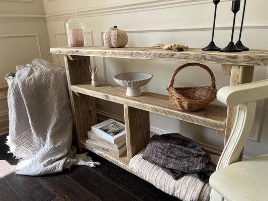 A farmhouse style wooden slim console table with one long shelf and two lower bottom shelves, in a living room setting (front view)