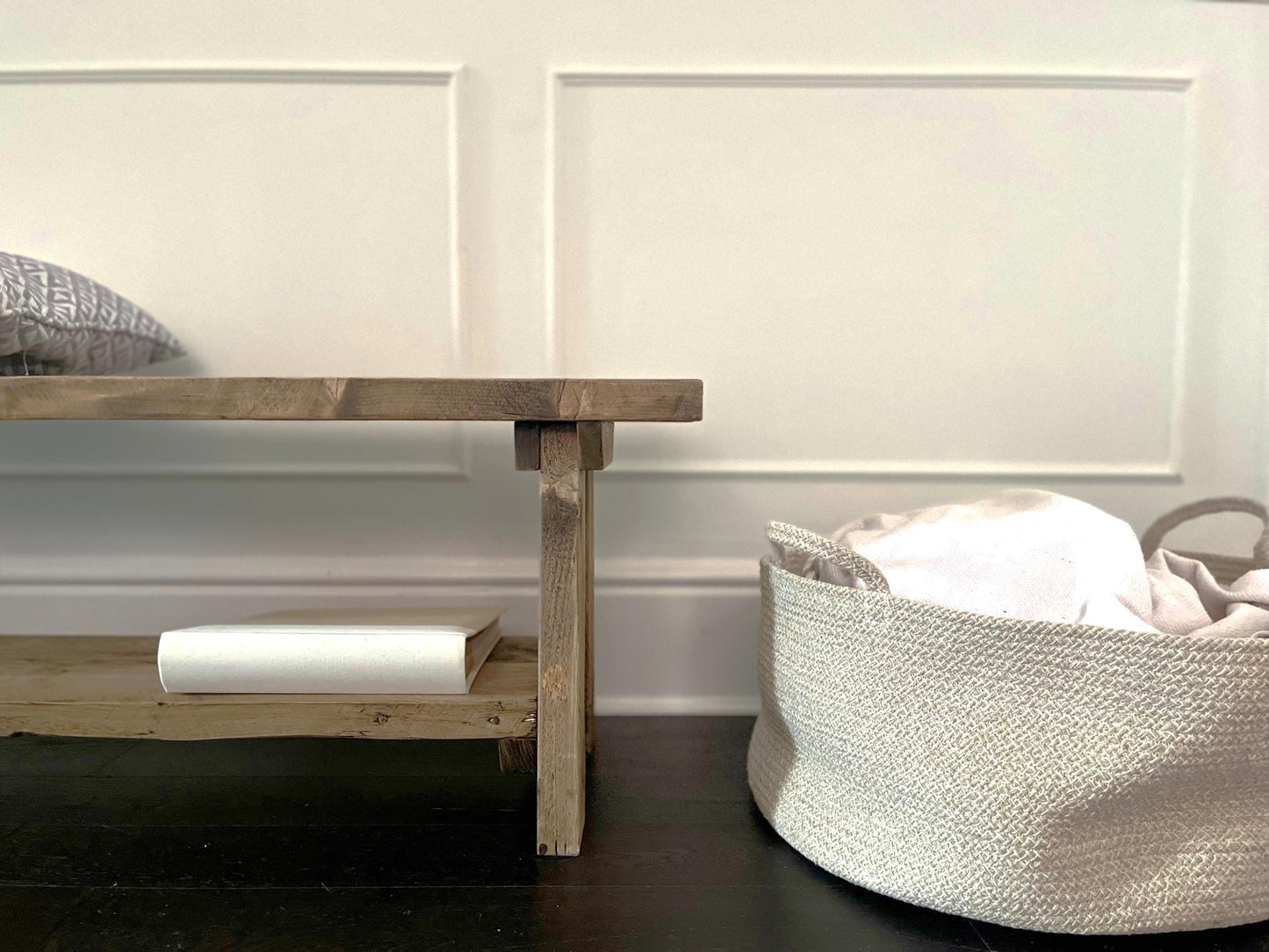 A farmhouse styled, rustic wooden bench with a bottom shelf, in an entryway  setting. (front view)