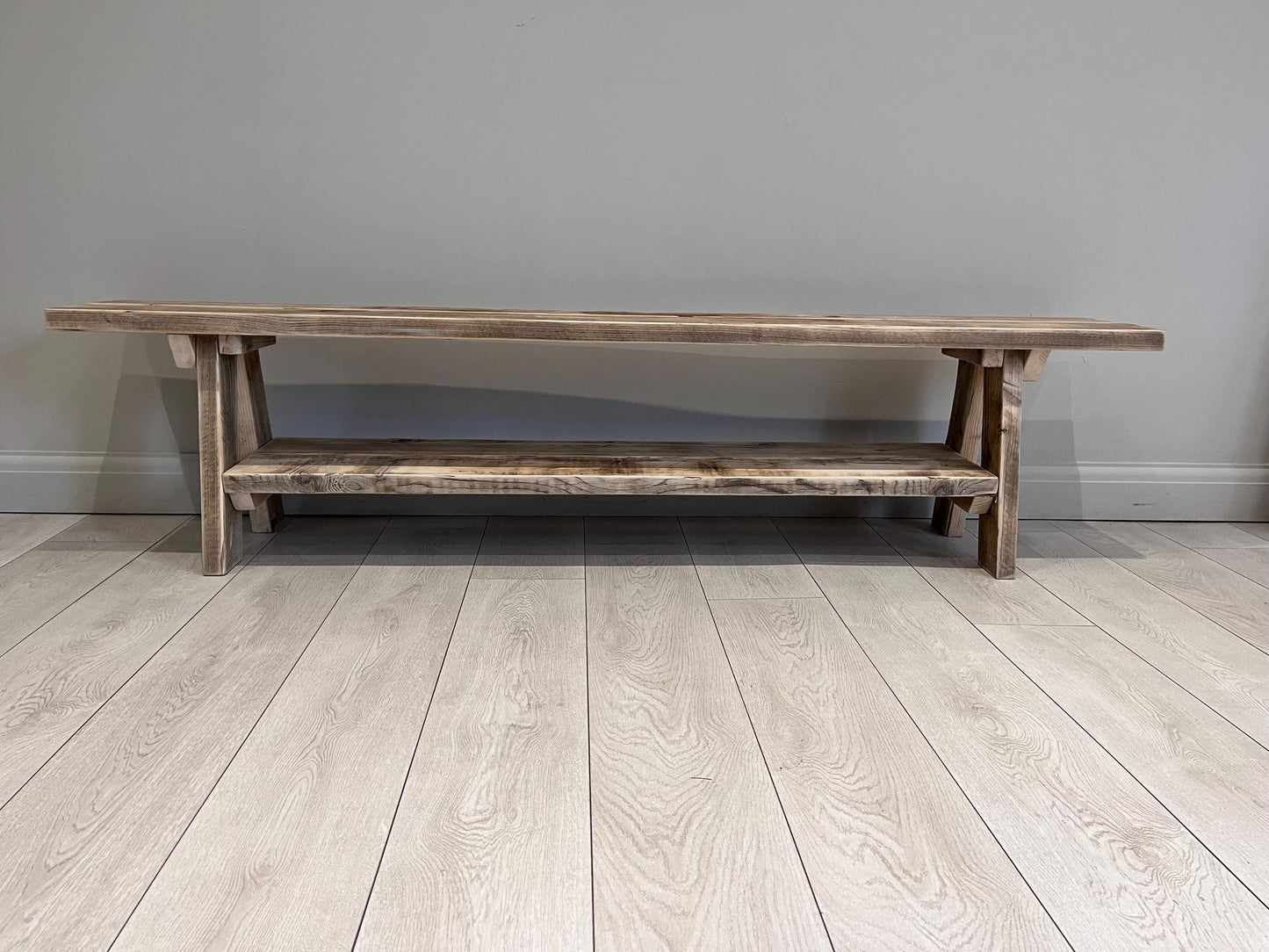 A farmhouse styled, rustic wooden bench with a bottom shelf, in an entryway  setting. (front view) Large version