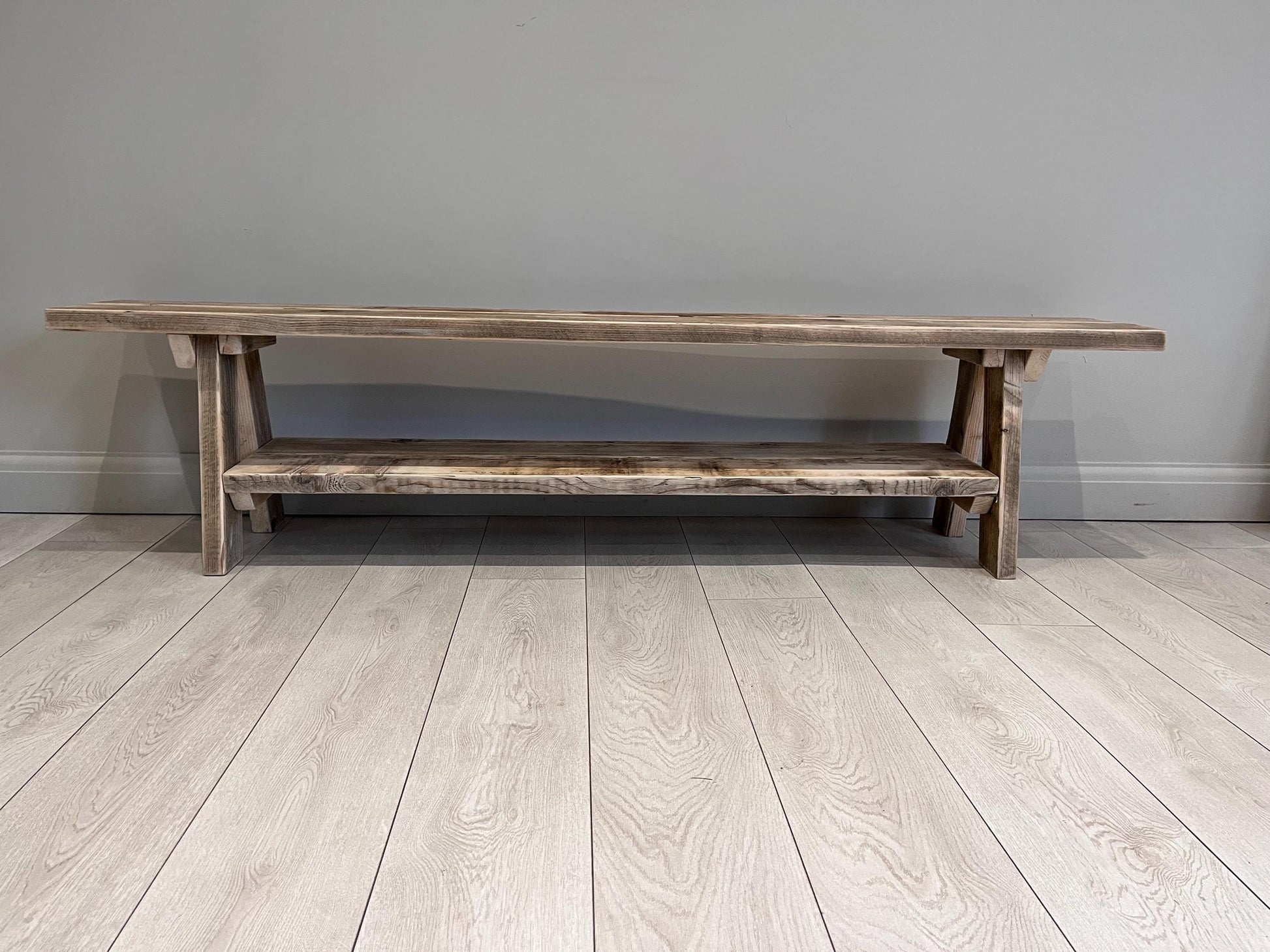 A farmhouse styled, rustic wooden bench with a bottom shelf, in an entryway  setting. (front view) Large version