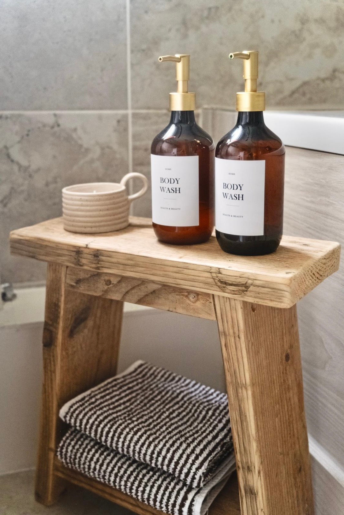 Two bottles of body wash on a wooden stool in a bathroom setting.