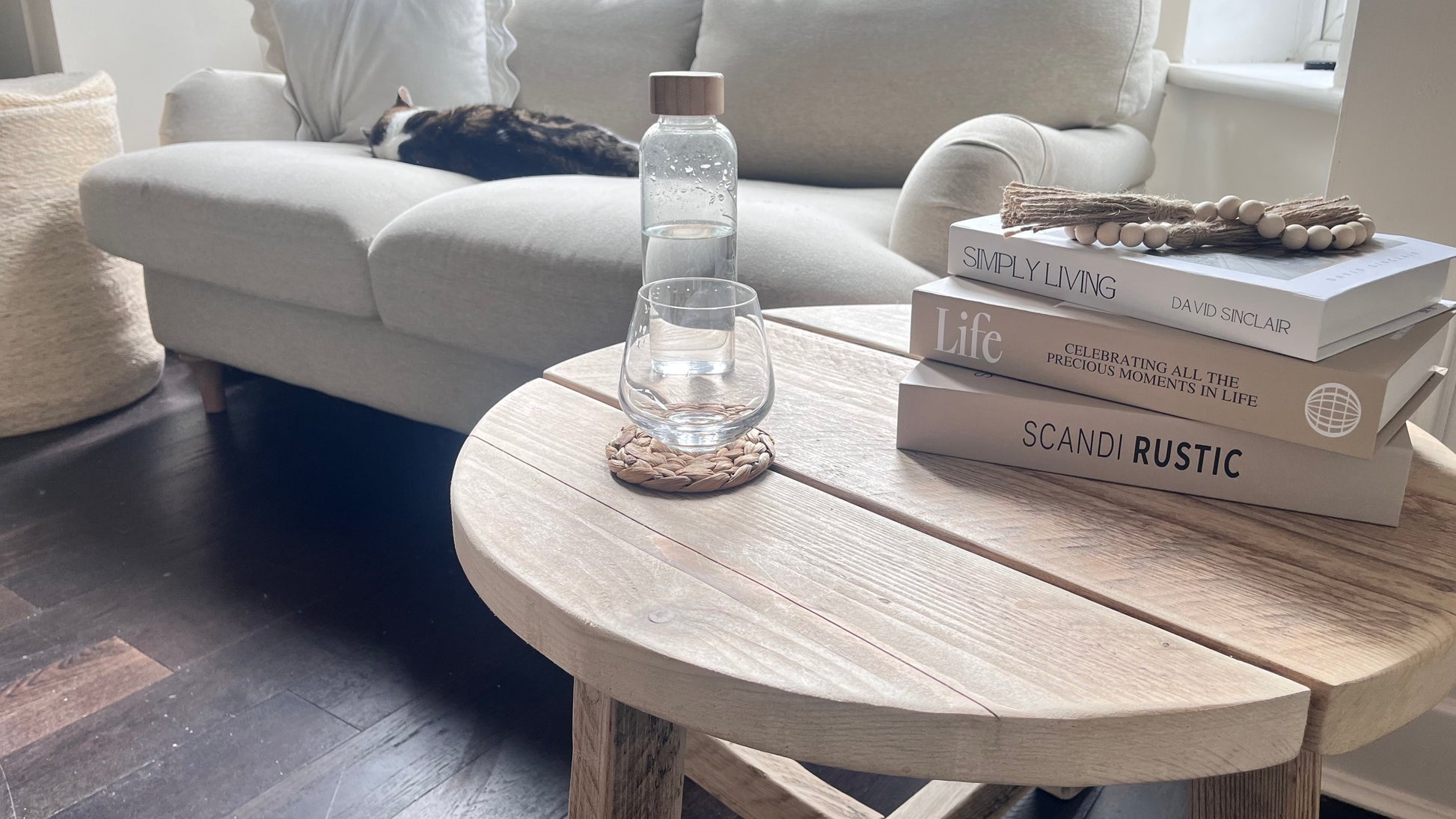 Light wooden coffee table with books and a water bottle in a living room setting.