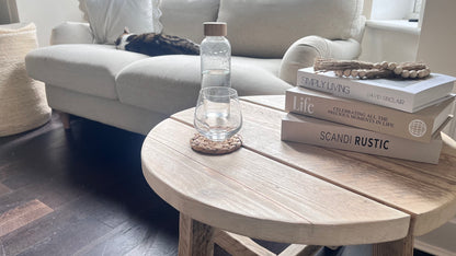 Light wooden coffee table with books and a water bottle in a living room setting.