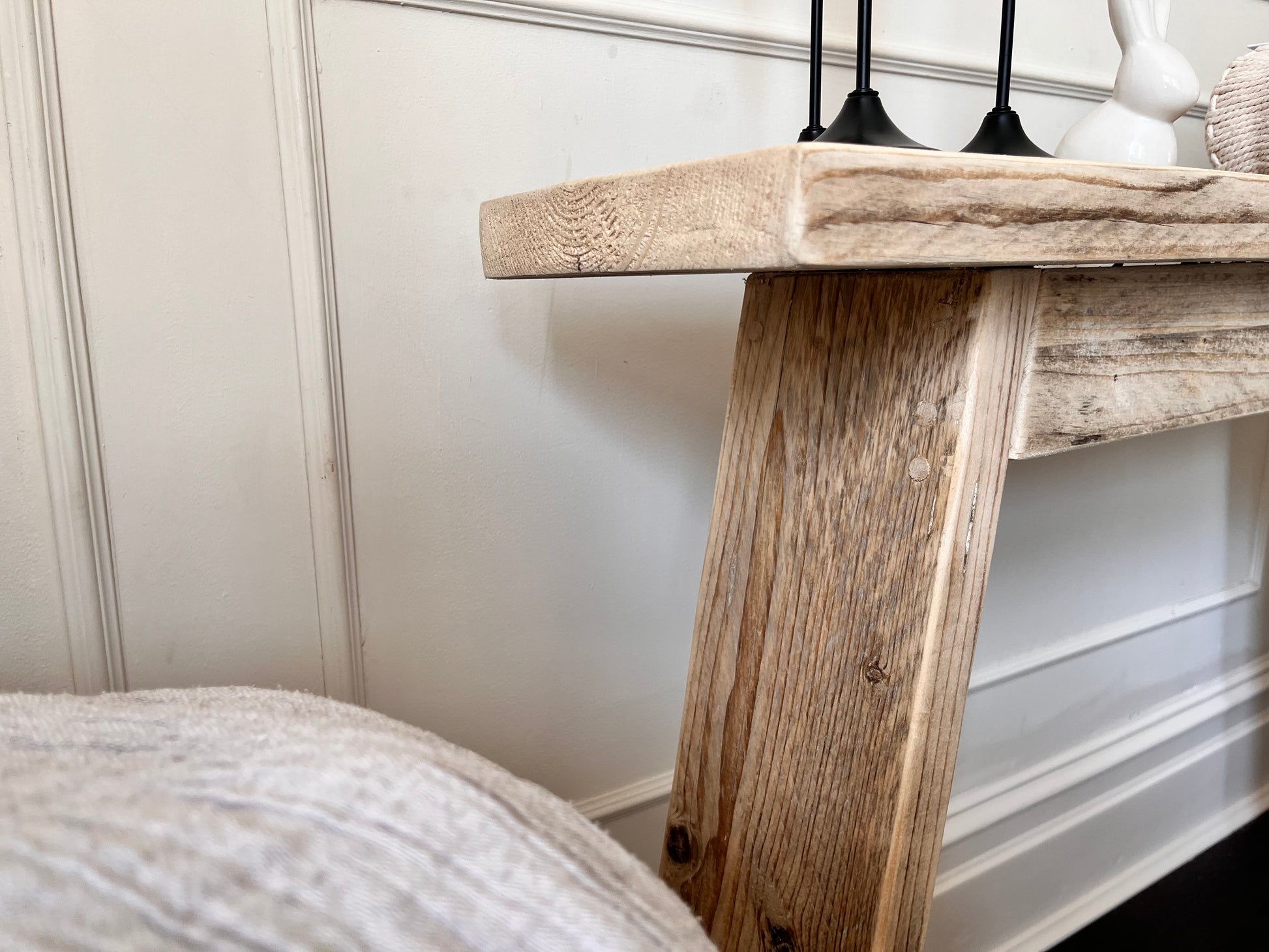 Wooden console table with decorative items against a white wall.