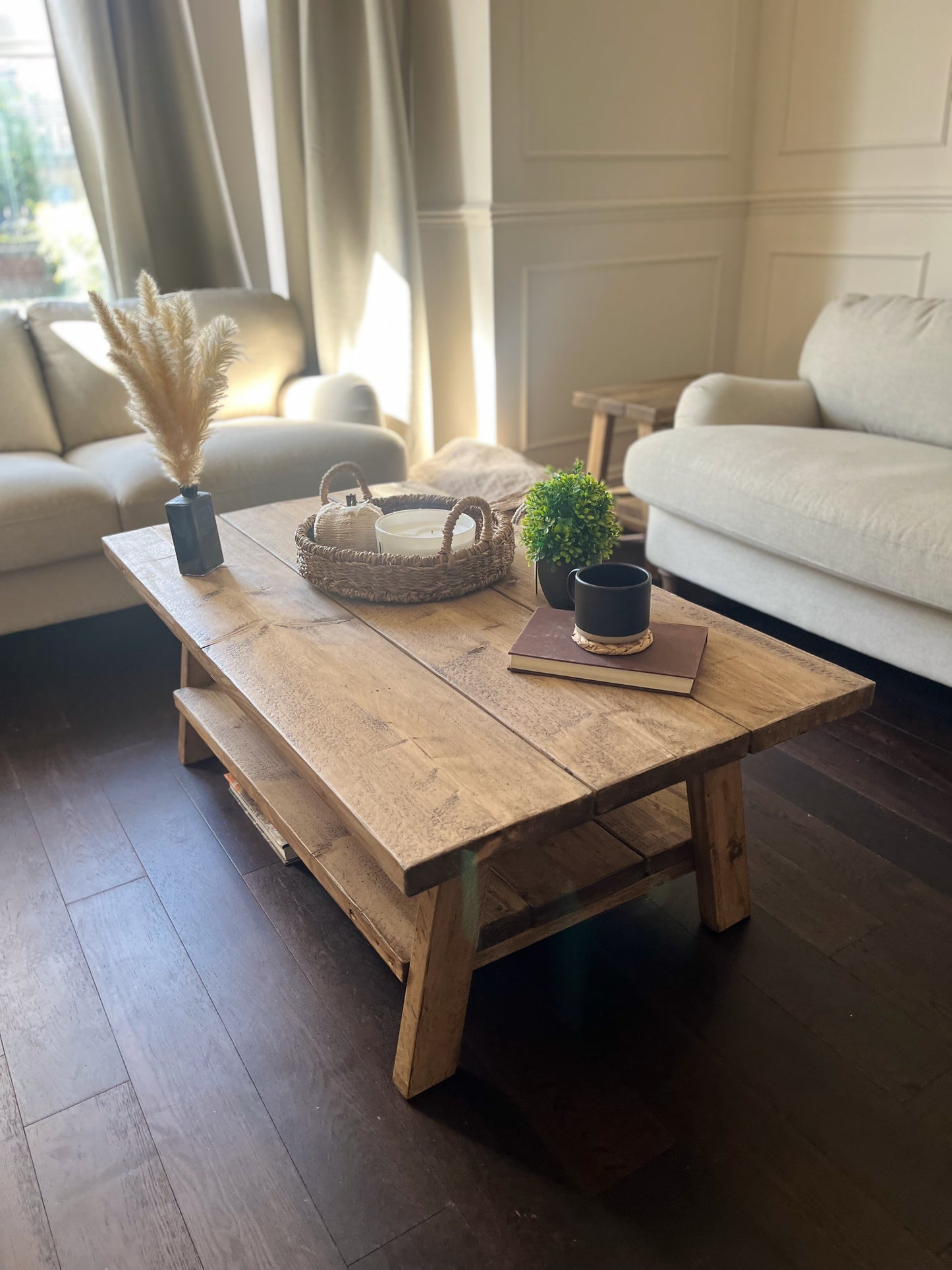 A farmhouse styled, rustic wooden coffee table, with a lower shelf in a living room setting.