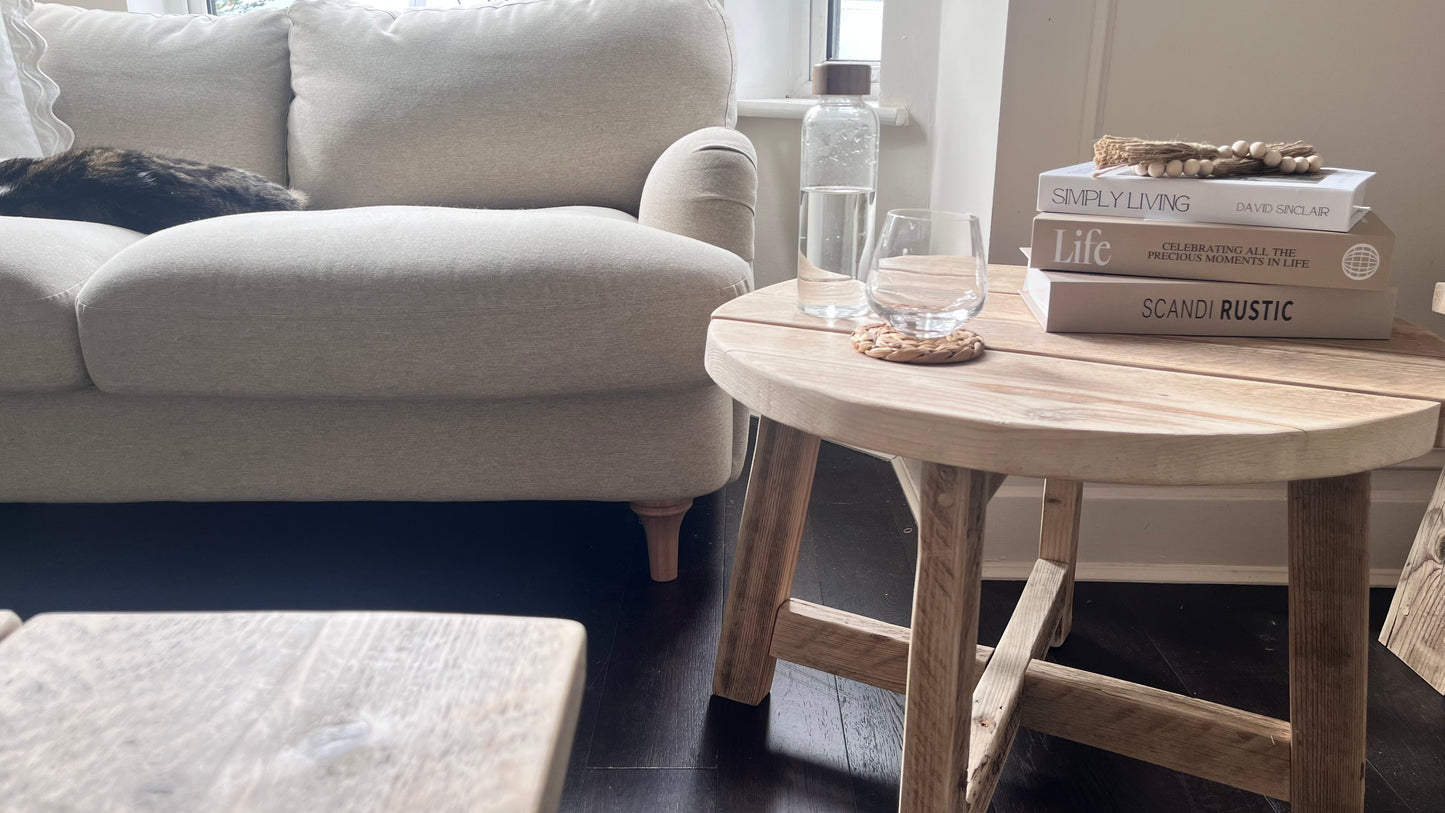Round wooden coffee table with books in a living room setting