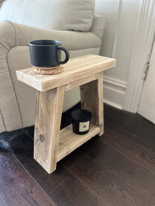 Small wooden side table with a black mug on top in a living room setting.