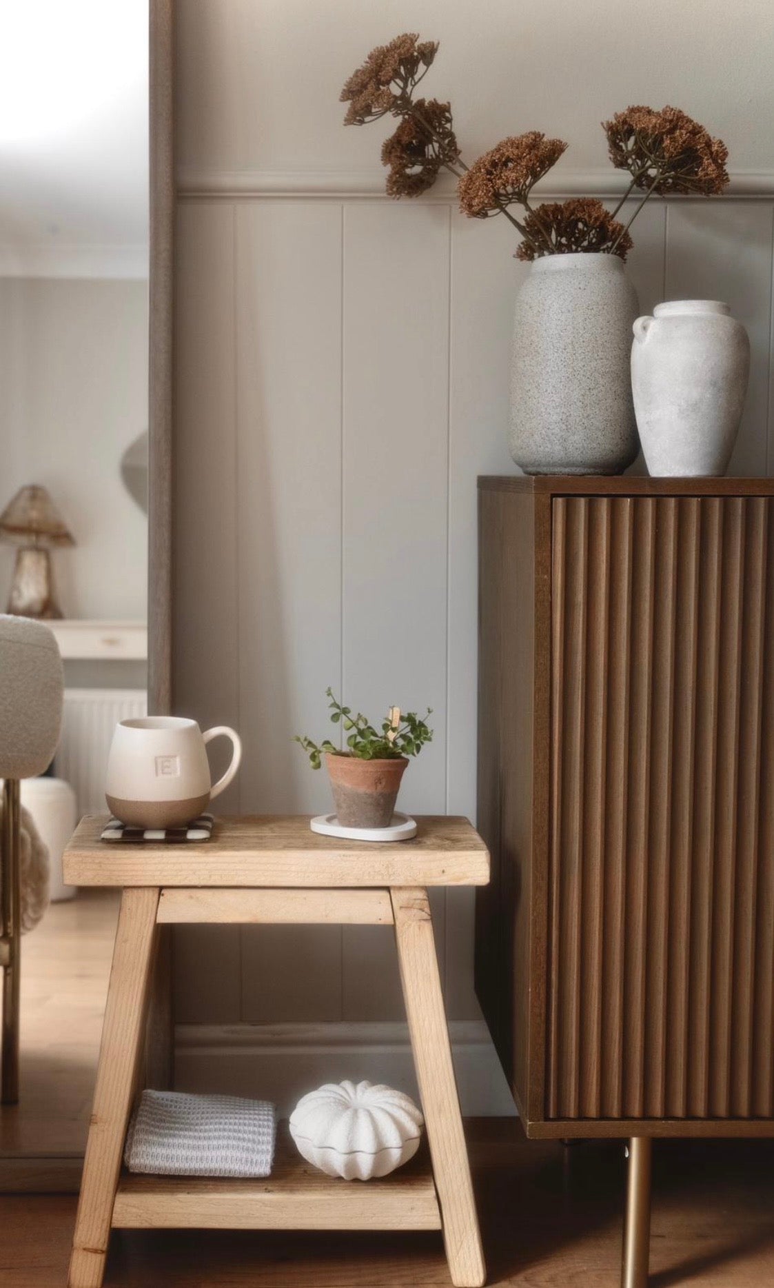Nestled corner with a wooden side table, white vases, and decorative items.