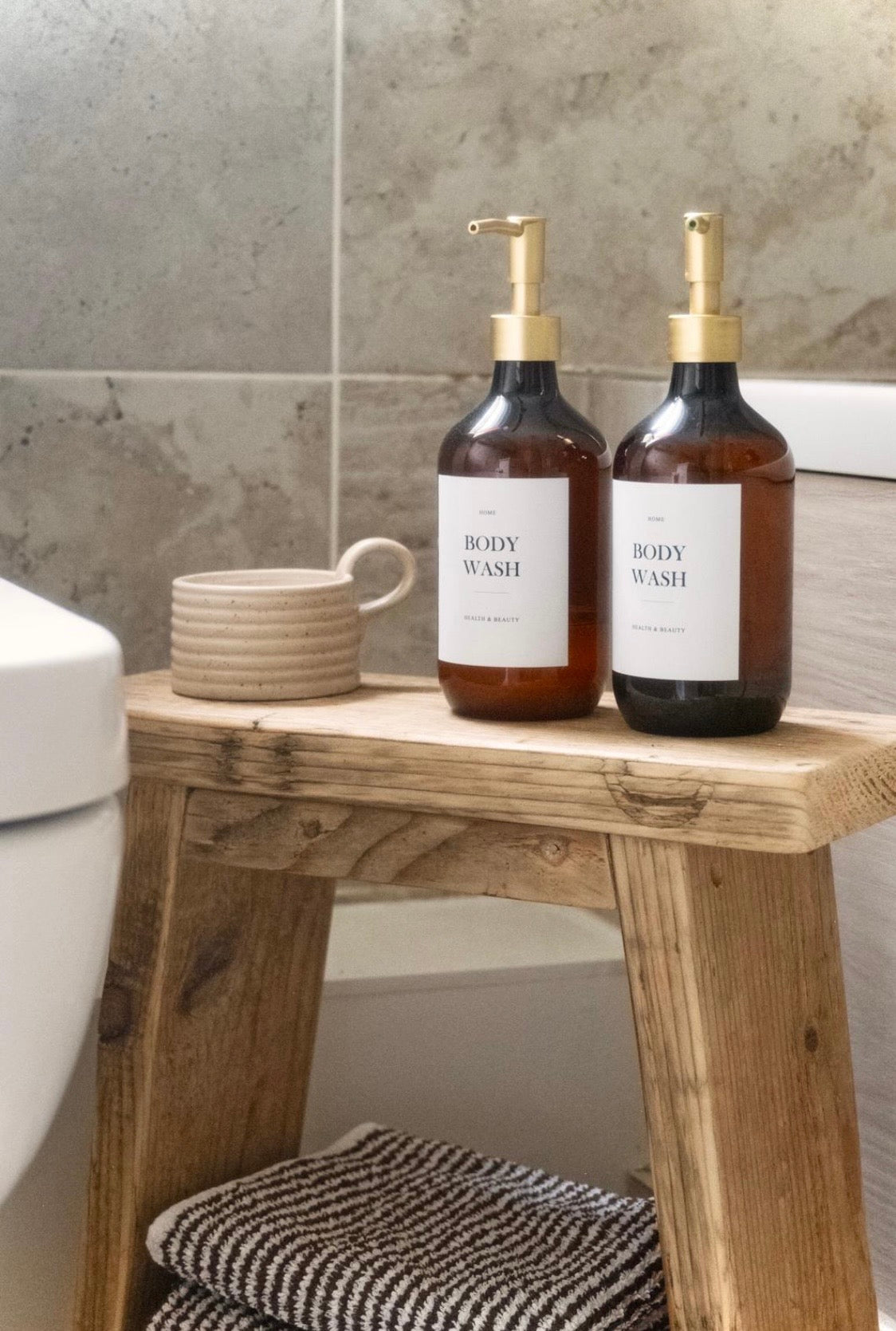 Two bottles of body wash on a wooden stool in a bathroom setting.