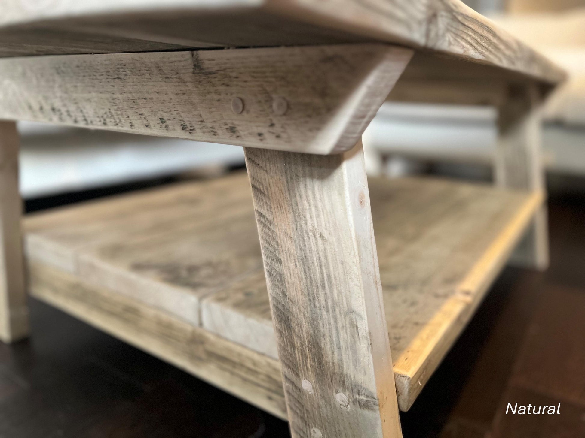 Close up of the craftsmanship of a farmhouse styled, rustic wooden coffee table, with a lower shelf in a living room setting.