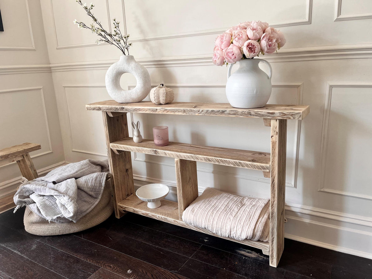 A farmhouse style wooden slim console table with one long shelf and two lower bottom shelves, in a living room setting (front view)