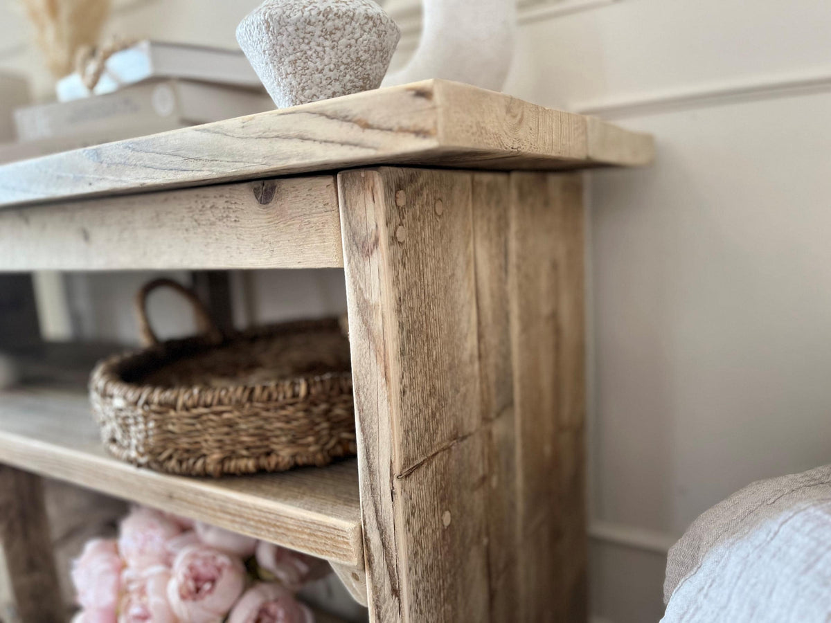 A close up image of a rustic wooden console table in a. farmhouse style. 