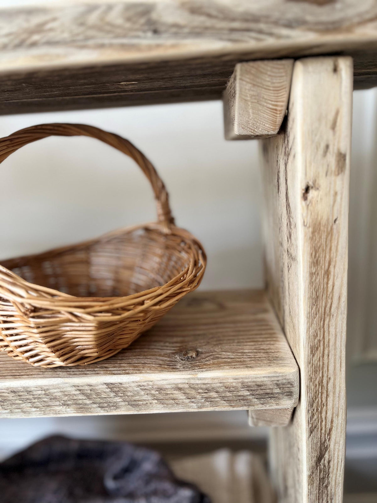 A close up of a farmhouse style wooden slim console table with one long shelf and two lower bottom shelves, in a living room setting (front view)