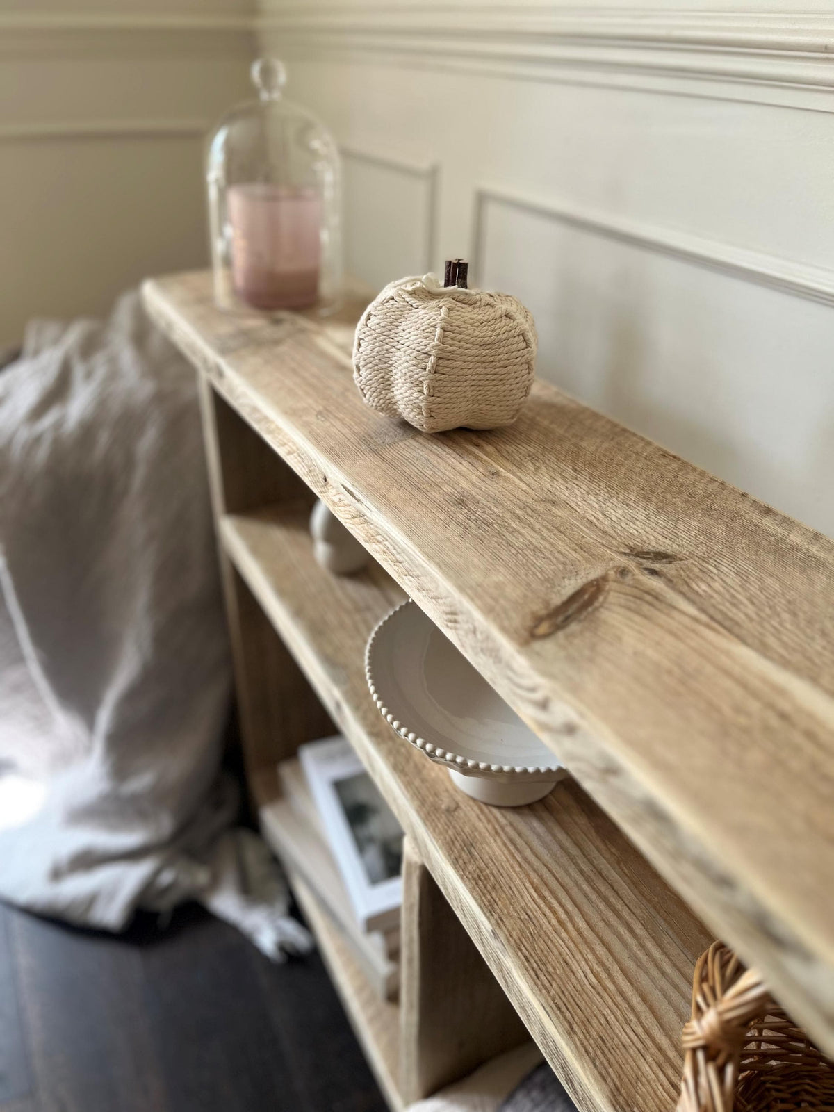 A farmhouse style wooden slim console table with one long shelf and two lower bottom shelves, in a living room setting (top view)