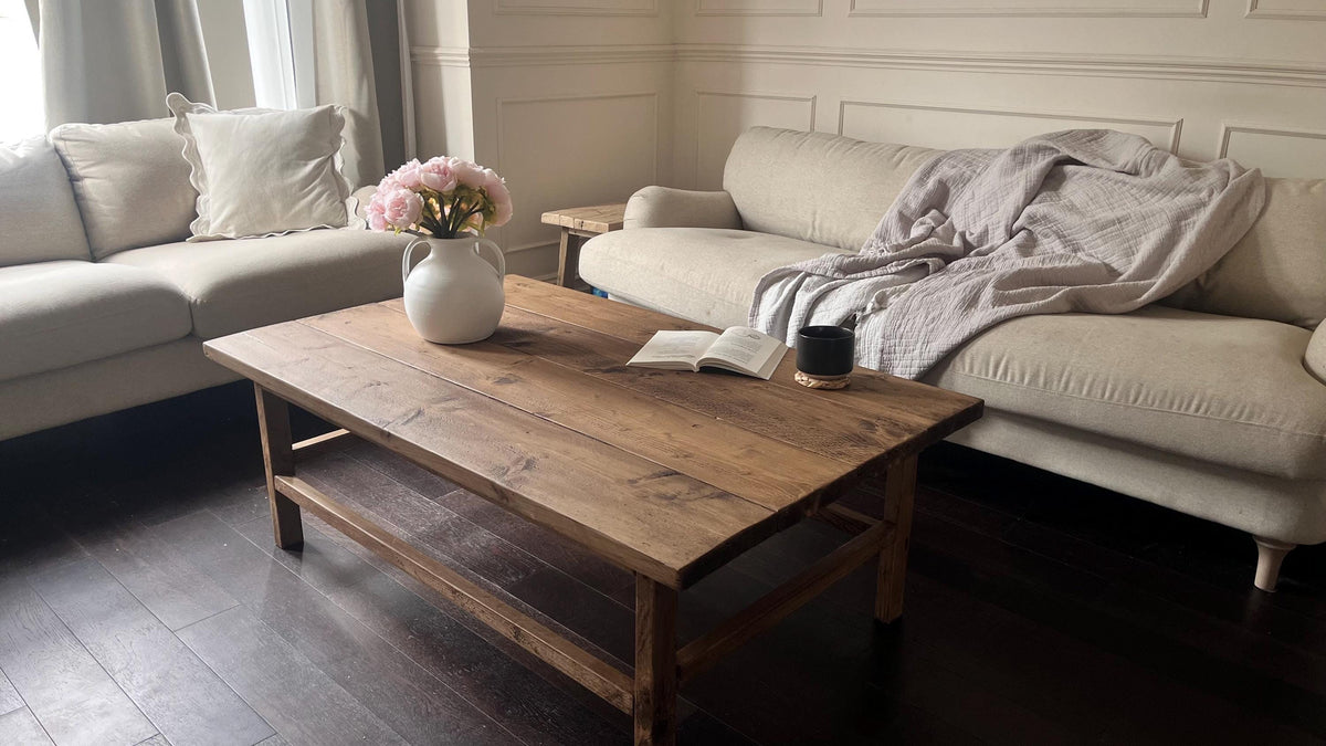 A farmhouse style wooden dark coffee table with a bottom shelf, in a living room setting (front view)