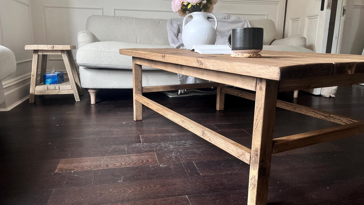 A farmhouse style wooden dark coffee table with a bottom shelf, in a living room setting (side view)