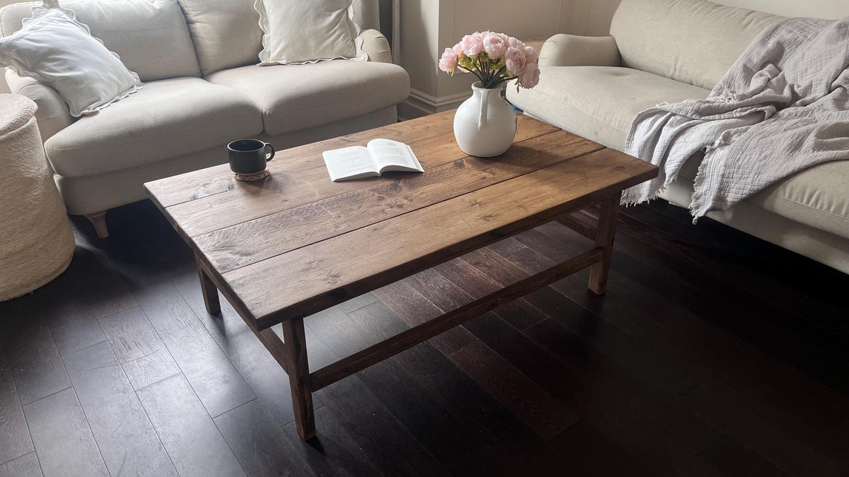 A farmhouse style wooden dark coffee table with a bottom shelf, in a living room setting (top view)