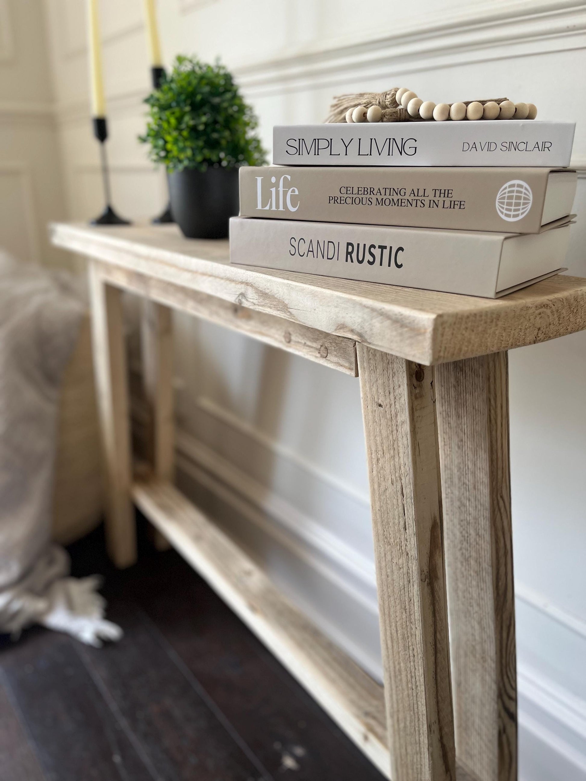 A farmhouse style rustic wooden slim console table with a bottom shelf, in a living room setting (side view)