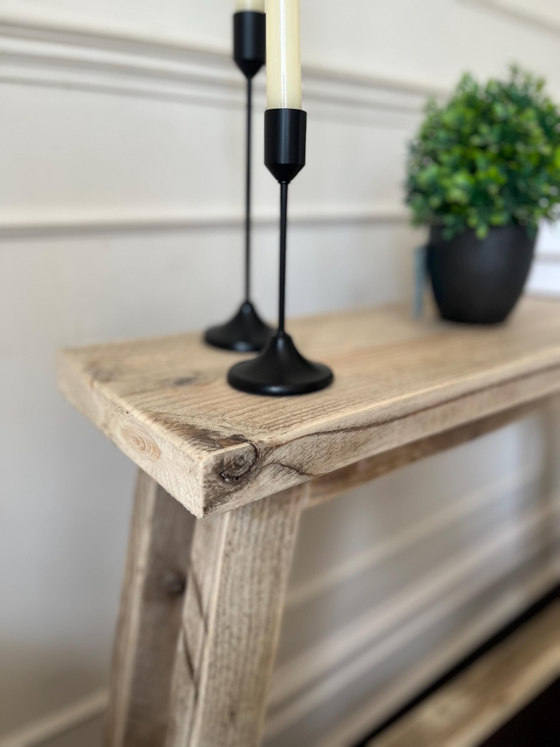 A farmhouse style rustic wooden slim console table with a bottom shelf, in a living room setting (side view)