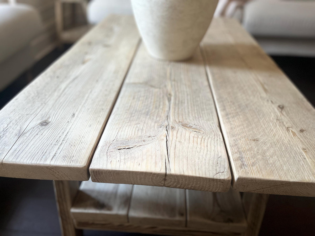 Wooden coffee table with a white vase on top in a living room setting