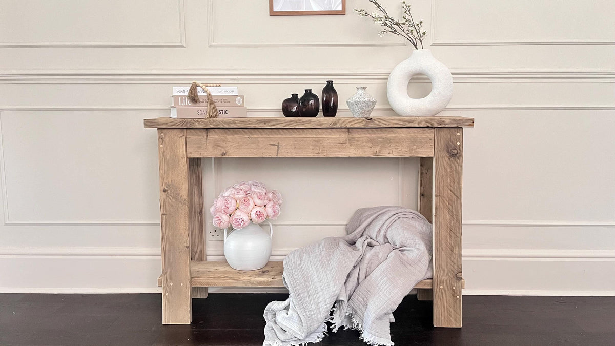 A farmhouse style wooden console table with a bottom shelf, in a living room setting (front view)