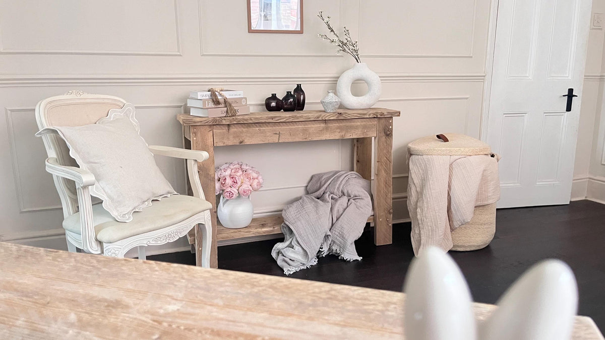 A farmhouse style rustic wooden console table with a bottom shelf, in a living room setting (front view)