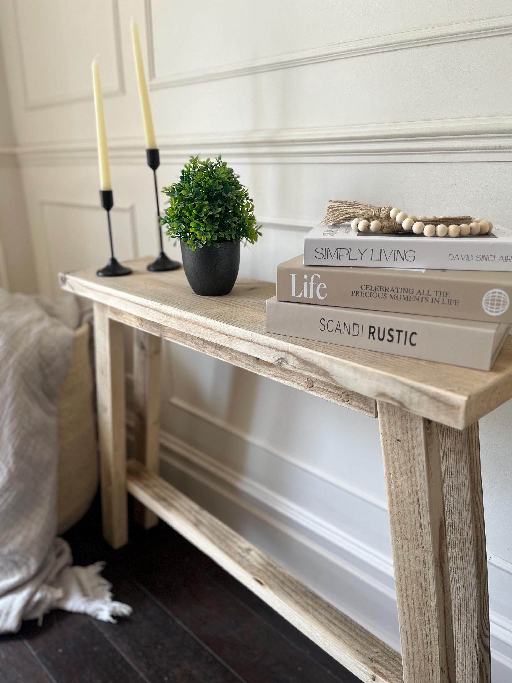A farmhouse style rustic wooden slim console table with a bottom shelf, in a living room setting (side view)