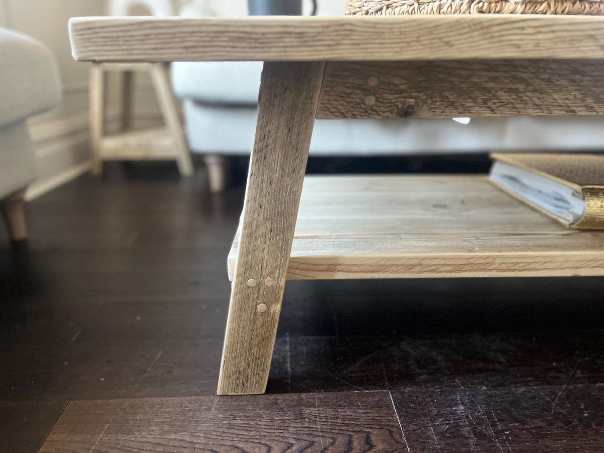 A farmhouse style rustic wooden coffee table with a bottom shelf, in a living room setting (front view)