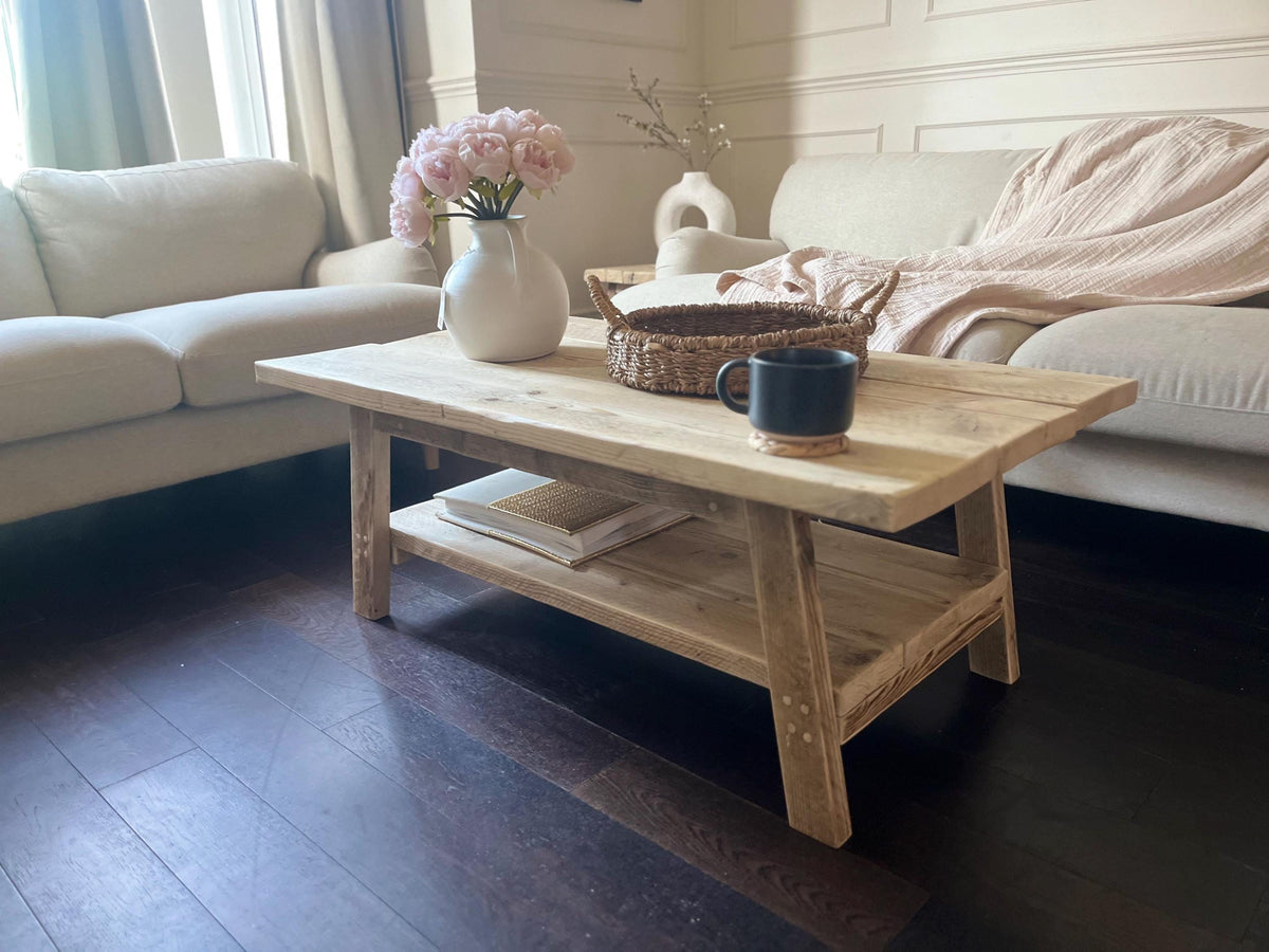 A farmhouse style rustic wooden coffee table with a bottom shelf, in a living room setting (front view)