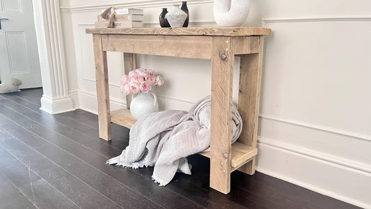A farmhouse style wooden console table with a bottom shelf, in a living room setting (front view)