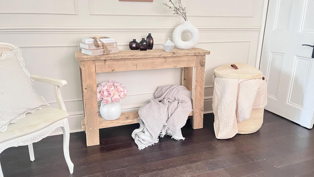 A farmhouse style rustic wooden console table with a bottom shelf, in a living room setting (front view)