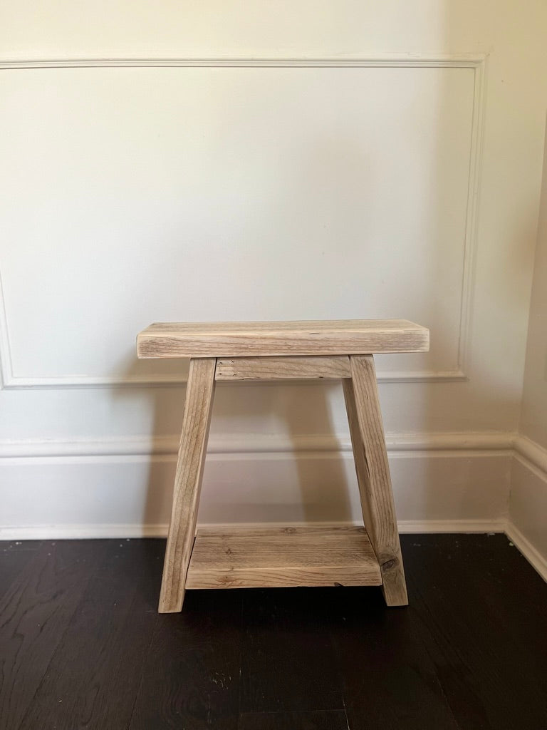 Wooden stool against a white wall